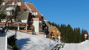Un sendero cubierto de nieve que conduce a un edificio con techo inclinado y barandillas de madera.