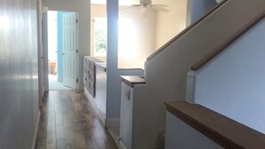 A hallway with wooden flooring, a ceiling fan, and a staircase with a wooden handrail. - A Grand  Teton getaway (Driggs)