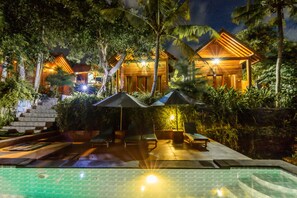 A resort with a swimming pool, lounge chairs, and umbrellas. - Green Valley Bungallow (Penida Island)