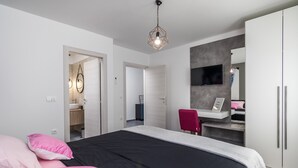 A modern bedroom with a large bed, a desk, a TV, and a wardrobe. - Villa Bellavu in Rakalj (Rakalj)