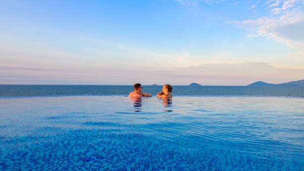 A couple in a infinity pool with a view of the sea and distant islands. - Fivitel Hoi An Hotel (Da Nang)