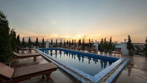 A rooftop pool with lounge chairs and potted plants, surrounded by trees and buildings. - Azalea Parkview Hotel (Vientiane)