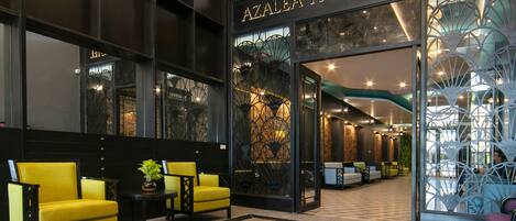 A lobby with a reception desk, yellow seating, and a large glass entrance to the Azalea Park View Hotel.
