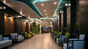 A hallway with seating areas, a patterned floor, and wall-mounted lighting. - Azalea Parkview Hotel (Vientiane)