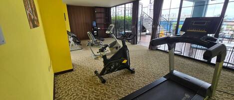 Ett hotellgym med konditionsutrustning, ett löpband och en styrketräningsmaskin.