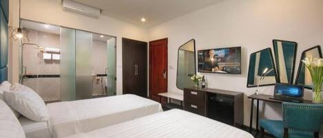 A hotel room with two beds, a desk, a chair, a TV, and a mirror.