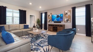 A modern living room with a sectional sofa, a coffee table, and a TV mounted on the wall. - 5🌟Clean Rated-Movie/Game Room, 3780 SF,❤️12p Dining (Davenport)
