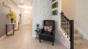 A modern interior with a black leather chair, a brick accent wall, and a staircase. - 5🌟Clean Rated-Movie/Game Room, 3780 SF,❤️12p Dining (Davenport)