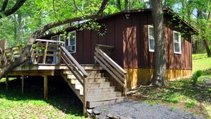 A wooden cabin with a staircase leading to a deck, surrounded by trees. - Bedrooms 2, Bathrooms 1, Sleeps 4 (Front Royal)