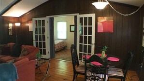 A cozy room with a wooden floor, a red sofa, a dining table with chairs, and a ceiling fan. - Bedrooms 2, Bathrooms 1, Sleeps 4 (Front Royal)