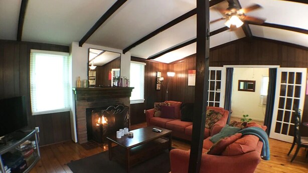 A cozy living room with a fireplace, wooden floors, a ceiling fan, and a red sofa. - Bedrooms 2, Bathrooms 1, Sleeps 4 (Front Royal)