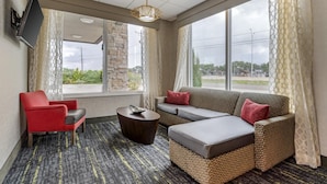 Una habitación de hotel con sofá, sillón y una pequeña mesa de centro.