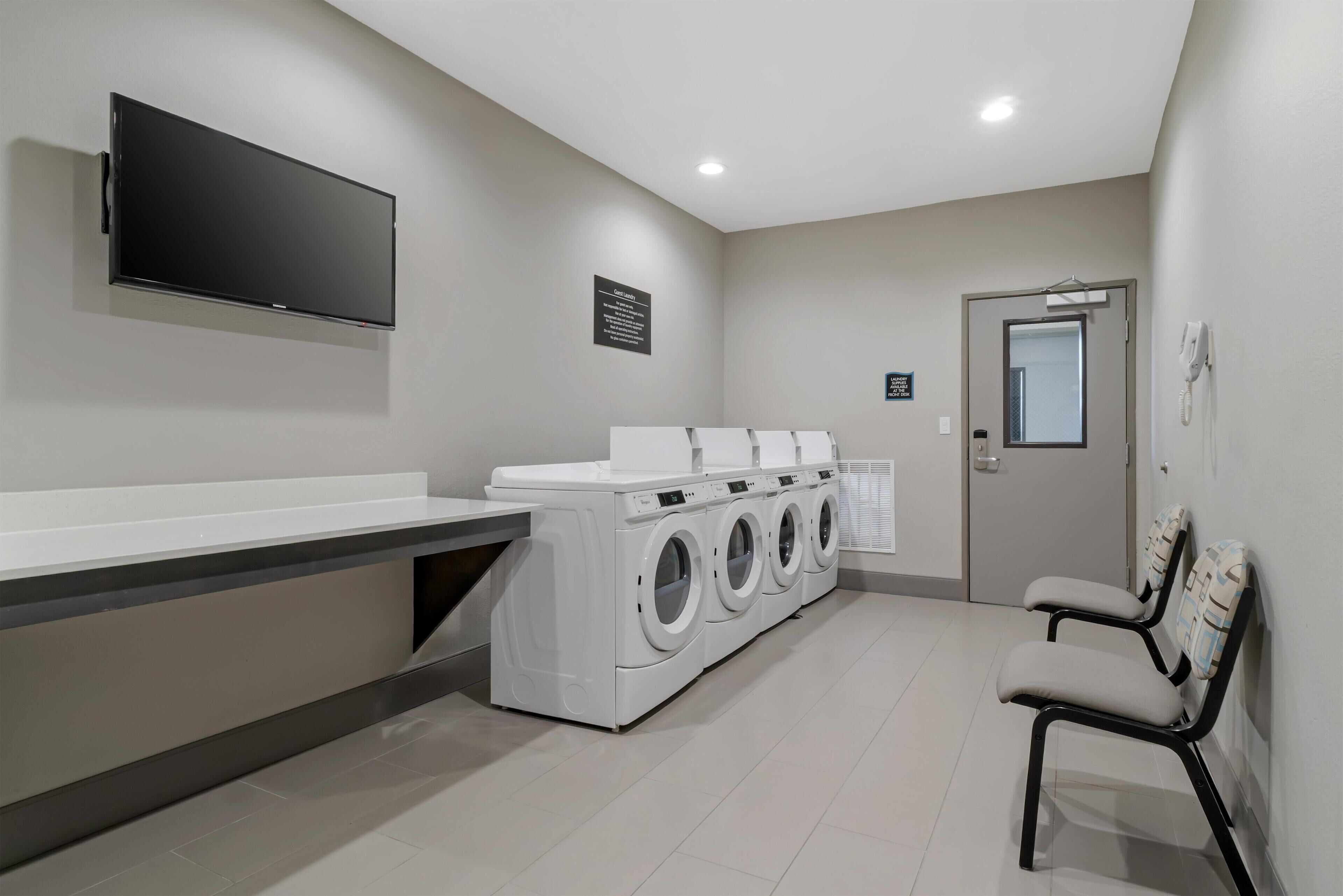 A laundry room with a flat-screen TV, a washing machine, and a dryer.