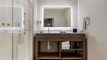 A modern bathroom with a glass shower enclosure, a wooden vanity with a mirror, and a towel rack.