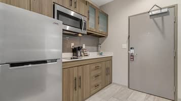 Una cocina moderna con un refrigerador de acero inoxidable, armarios de madera, un microondas y una cafetera.