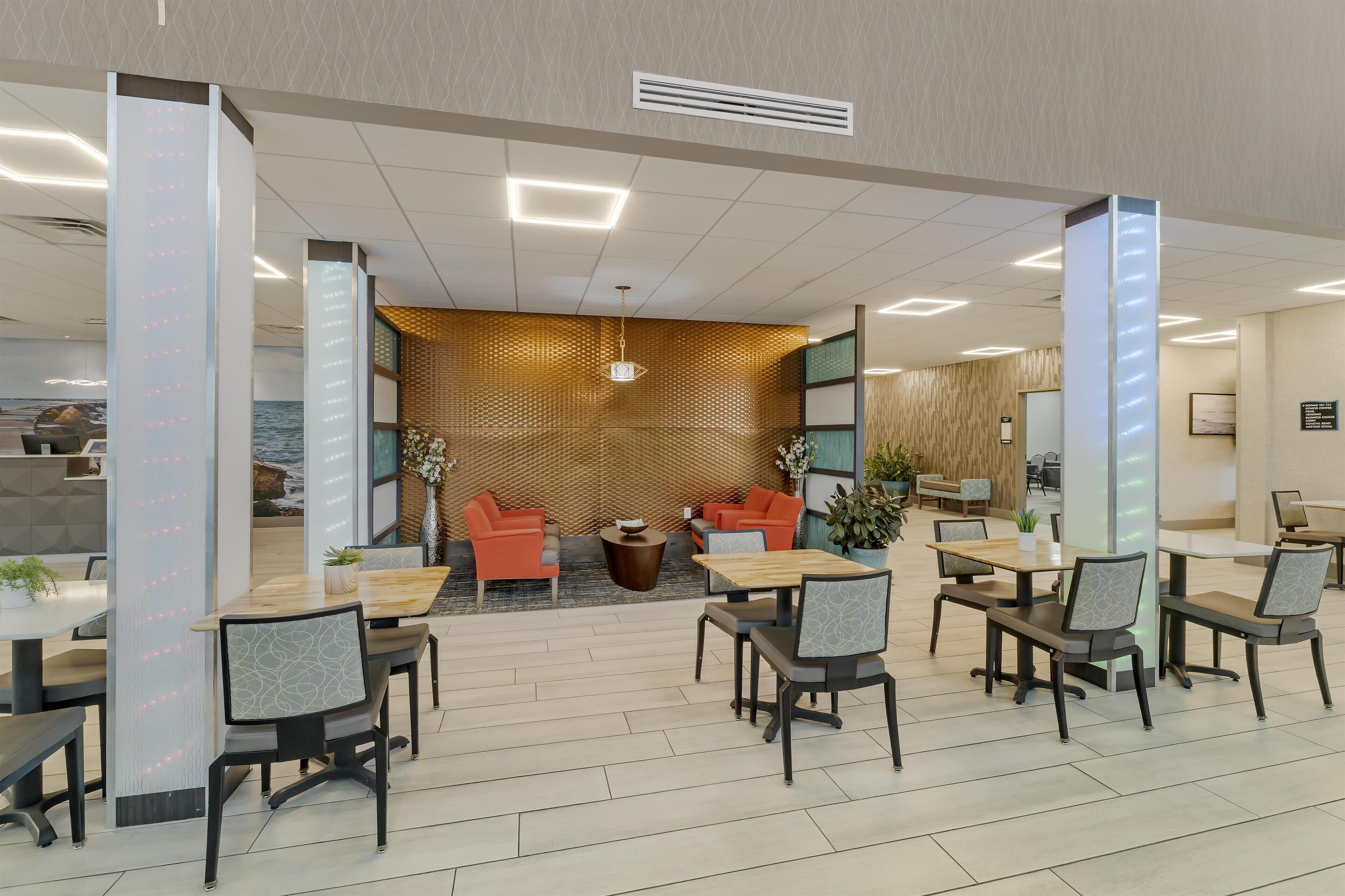 A modern indoor space with a reception area, seating arrangements, and a view of the sea through a patterned wall.