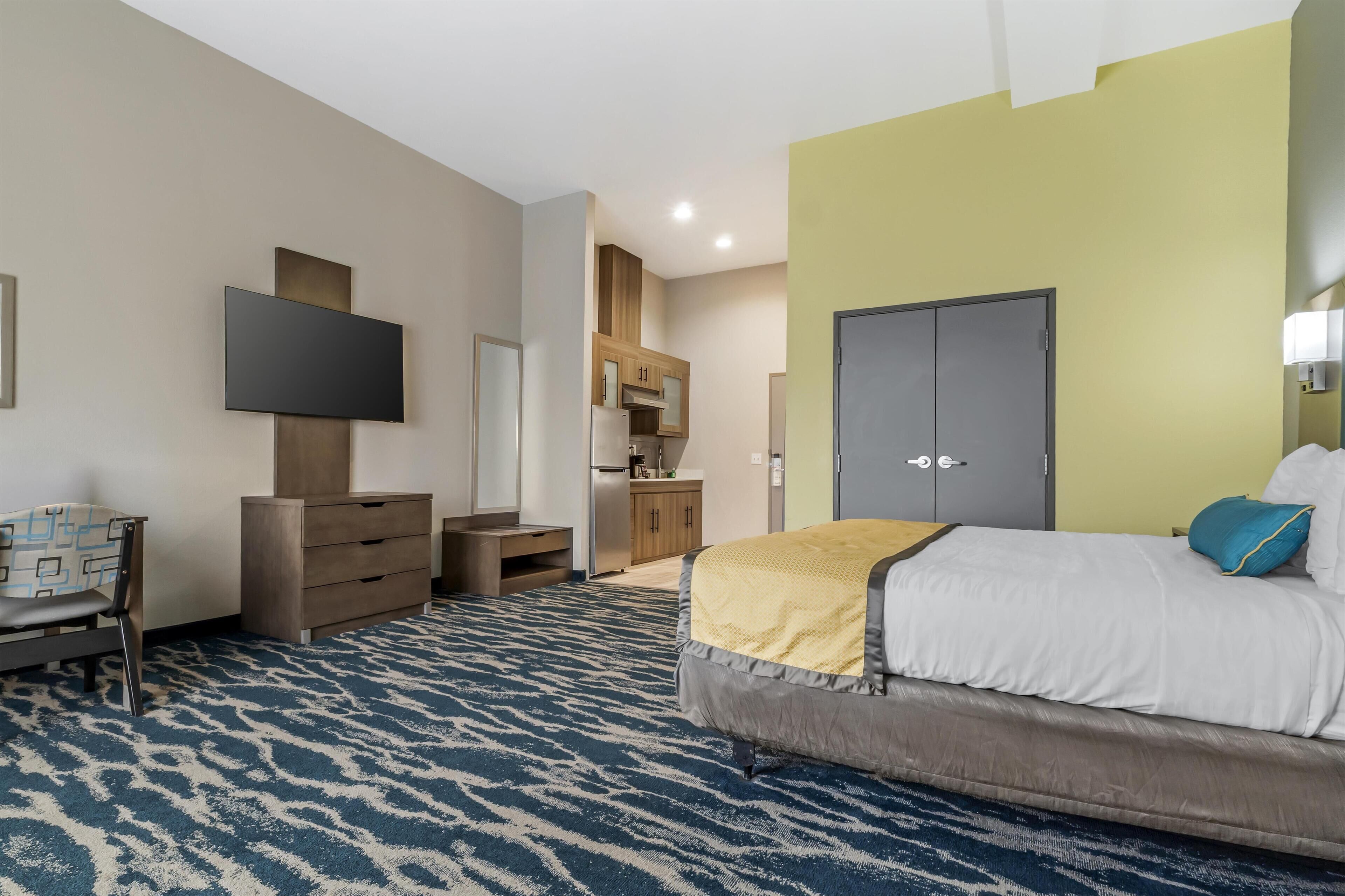 Une chambre d’hôtel équipée d’un lit, d’une télévision, d’une armoire, d’un bureau et d’une kitchenette.