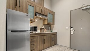 Una cocina moderna con un refrigerador de acero inoxidable, armarios de madera y un microondas integrado.