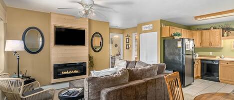 A living room with a fireplace, a television, and a dining area with a table and chairs.