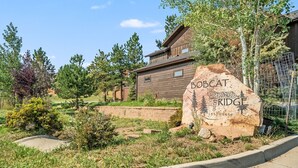 A rustic wooden building with a large rock sign labeled "BOBCAT FRIDGE" and the years "1437-1459".