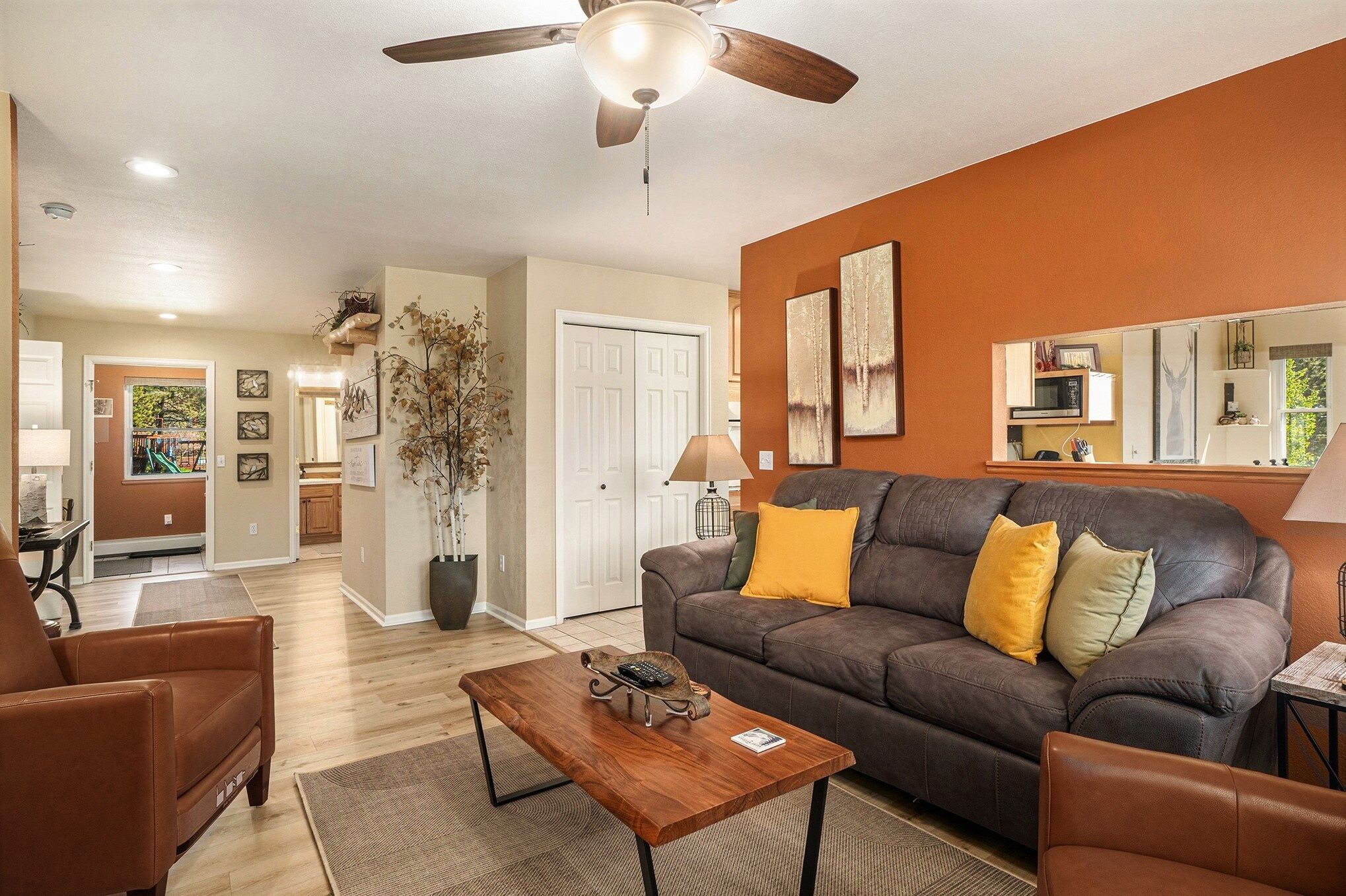 A living room with a brown leather sofa, a wooden coffee table, and a ceiling fan.