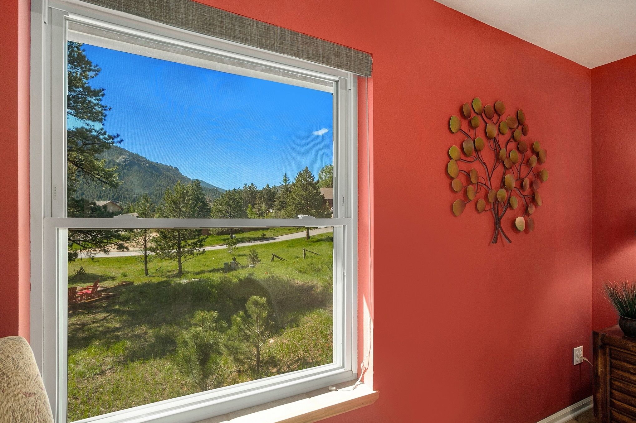 Una habitación con un ventanal grande que ofrece vistas a un paisaje verde y montañas.