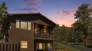 A two-story building with a balcony, a porch with chairs, and a stone wall.