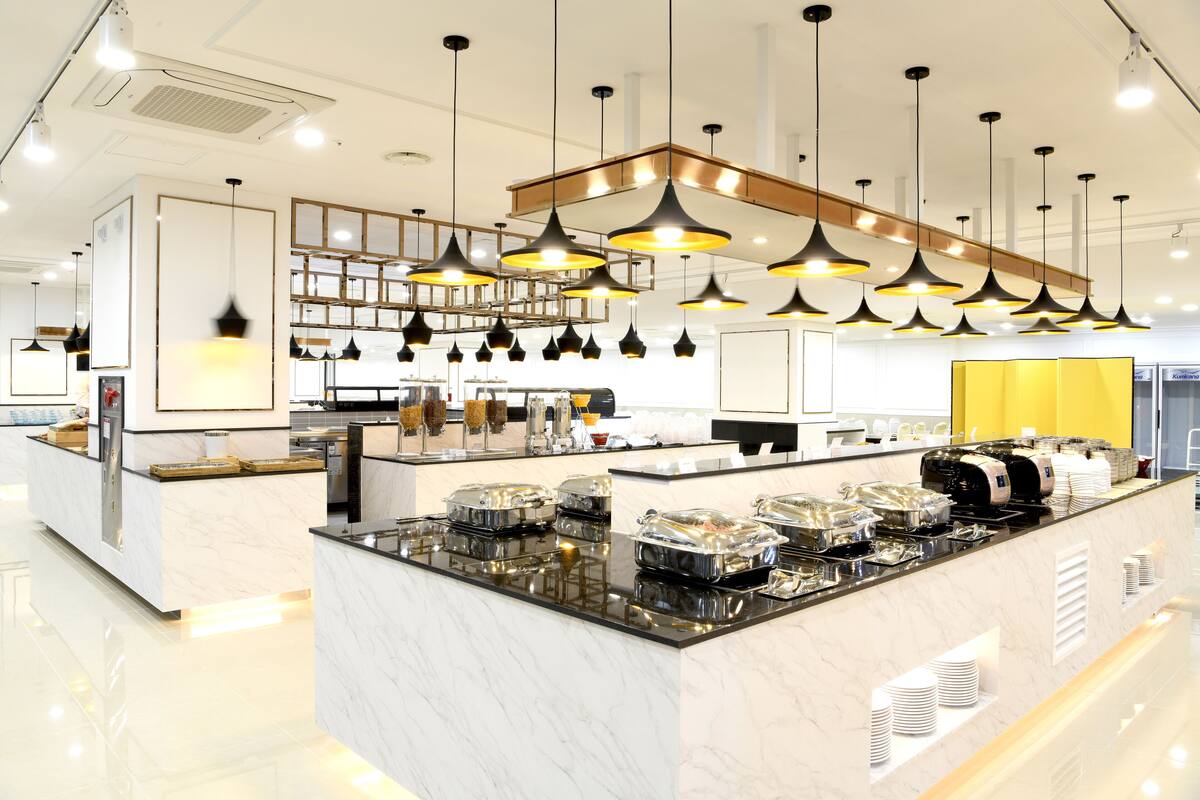 Een moderne keuken met een marmeren aanrecht, zwarte hanglampen en een centraal eiland met bewaarpotten.