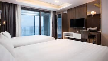 A hotel room with two beds, a desk, a chair, a TV, and a balcony with curtains.