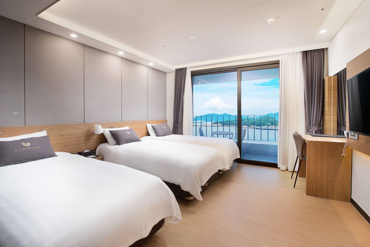 Een hotelkamer met twee bedden, een televisie en een balkon met uitzicht.