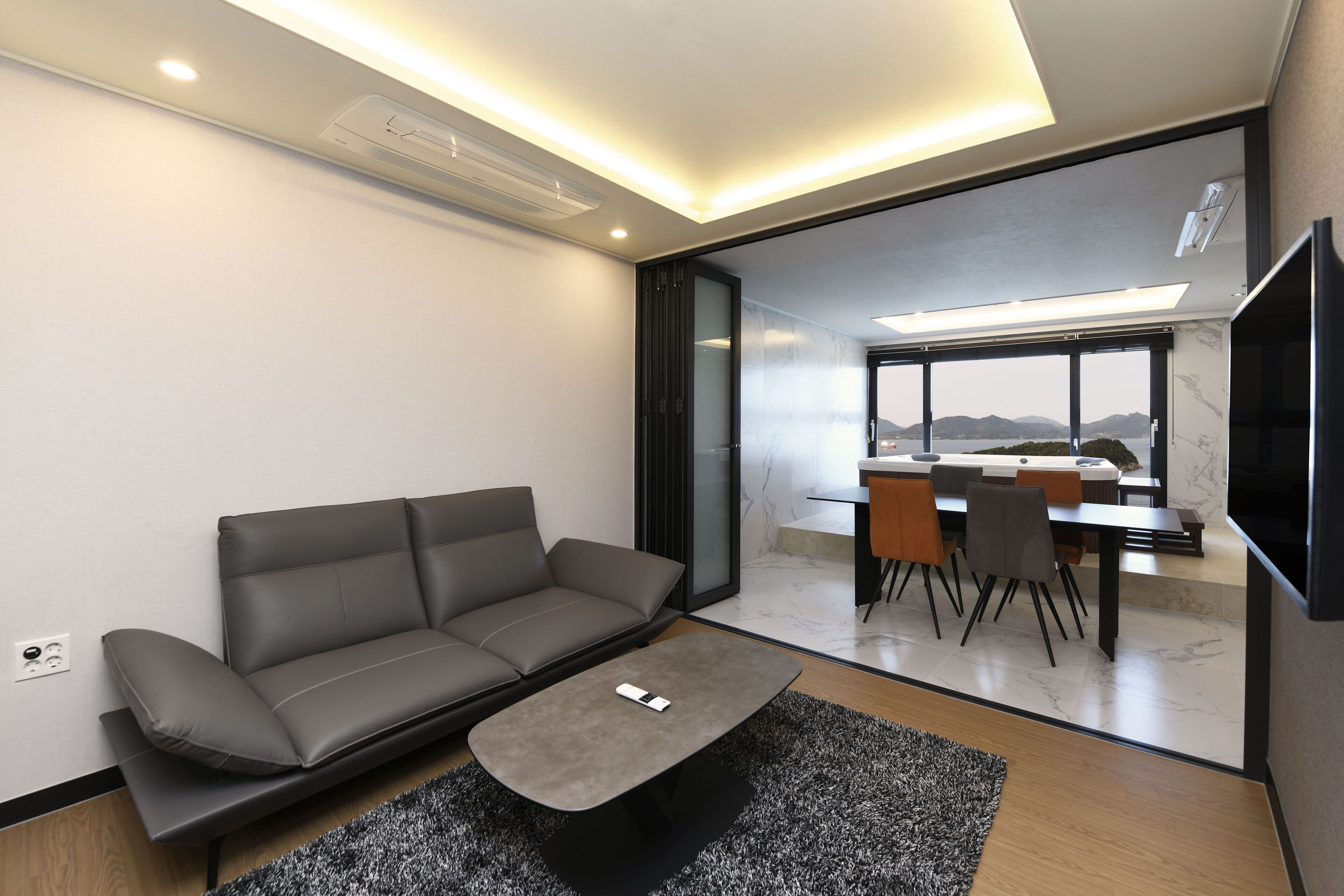 Een moderne woonkamer met een grijze bank, een salontafel en een eethoek met een tafel en stoelen.
