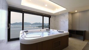 A modern bathroom with a large bathtub, a view of the sea, and a minimalist design. - Utop Marina Hotel & Resort (Yeosu)