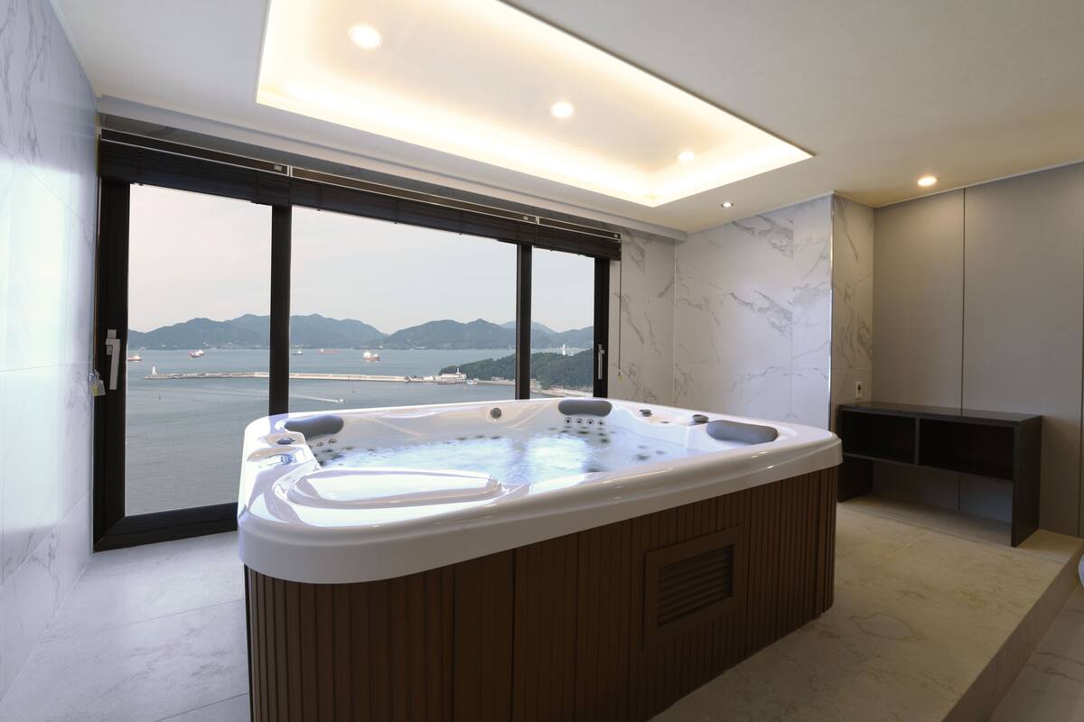 Een moderne badkamer met een groot bad, uitzicht op zee en een minimalistisch design.