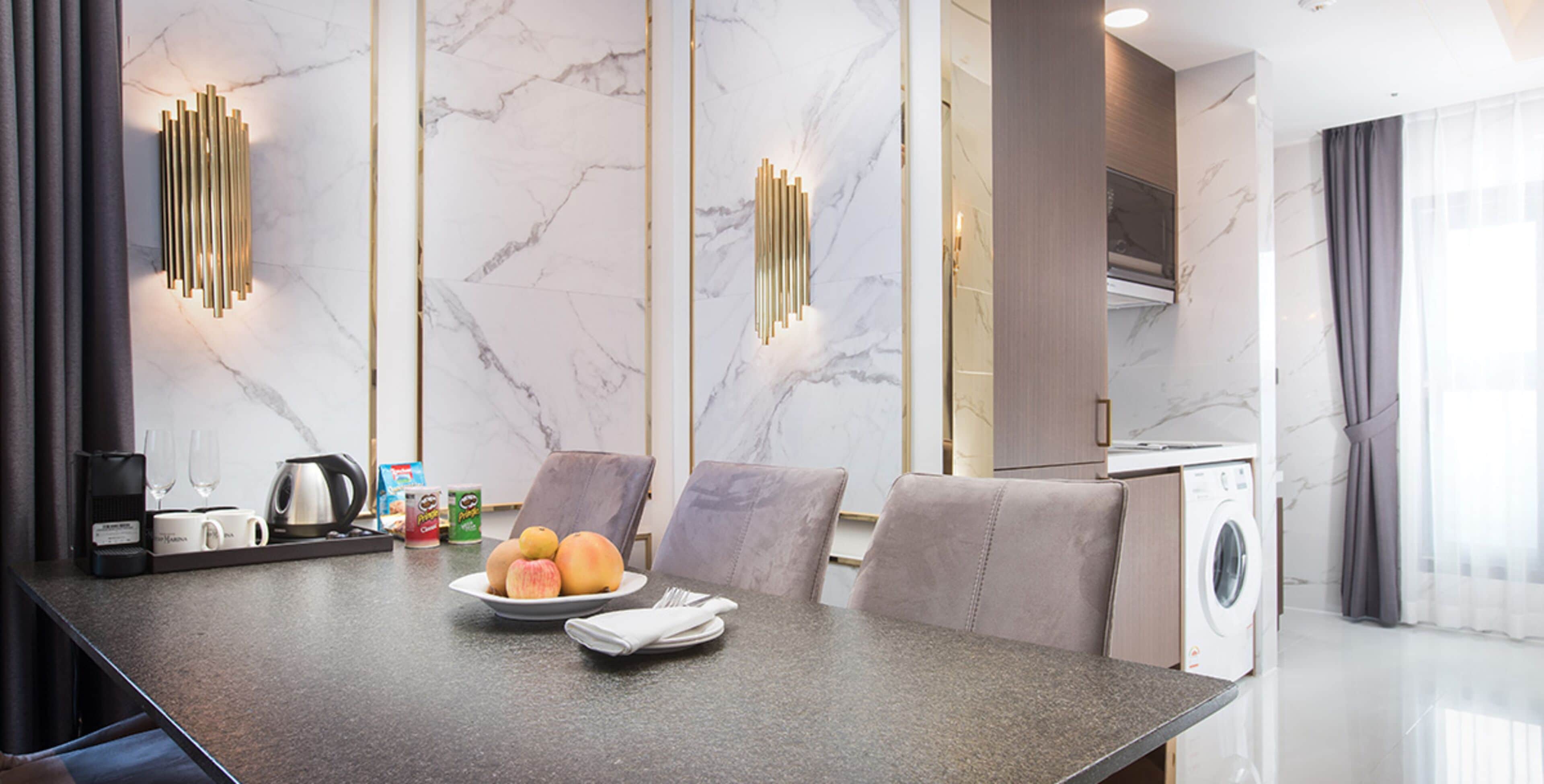 A modern kitchen with a marble backsplash, a built-in washing machine, and a dining area with a marble table and chairs.