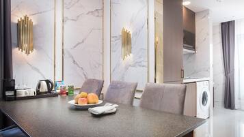 A modern kitchen with a marble backsplash, a built-in washing machine, and a dining area with a marble table and chairs.