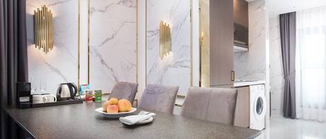 A modern kitchen with a marble backsplash, a built-in washing machine, and a dining area with a marble table and chairs.