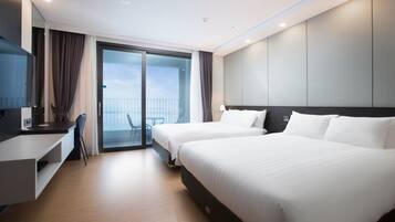A modern hotel room with two beds, a desk, and a balcony with a view.