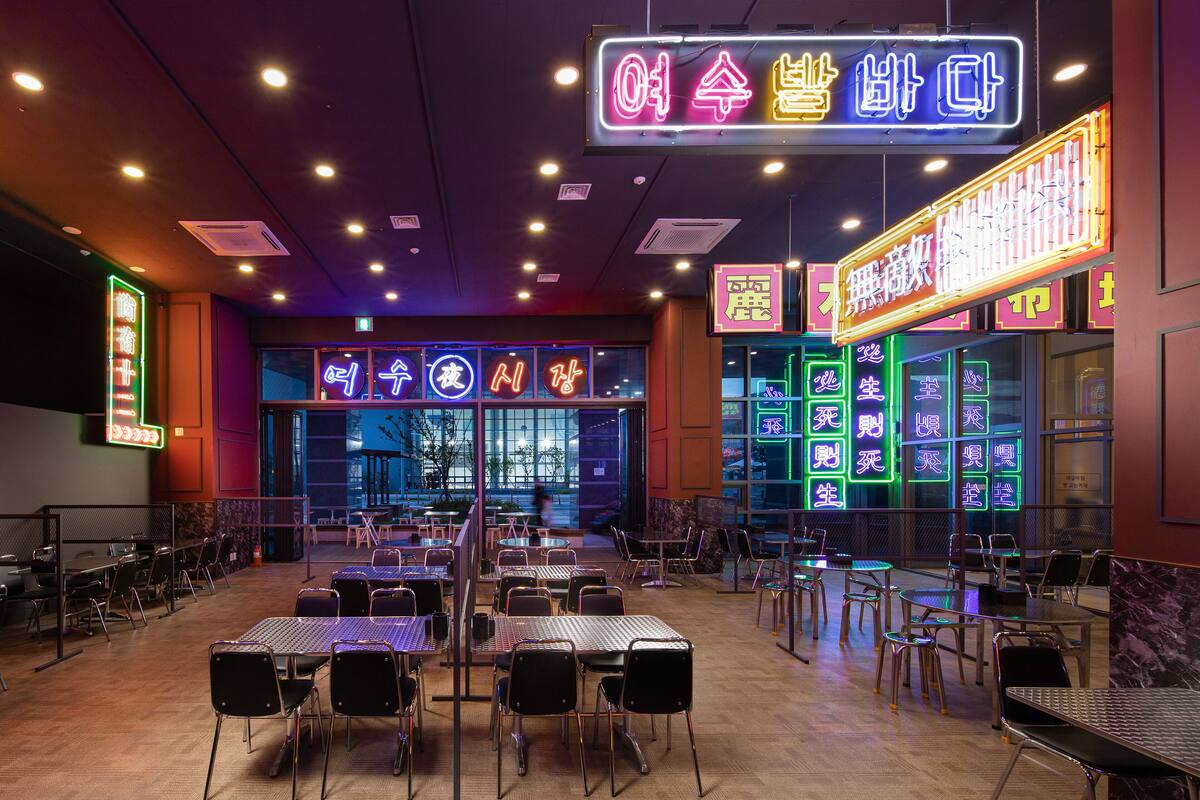 Een restaurant met neonreclames en tafels en stoelen klaar voor diners.
