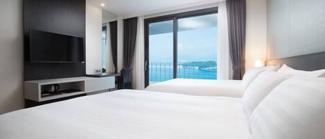 Una habitación de hotel moderna con una cama grande, un televisor de pantalla plana en la pared y un balcón con vista al mar.
