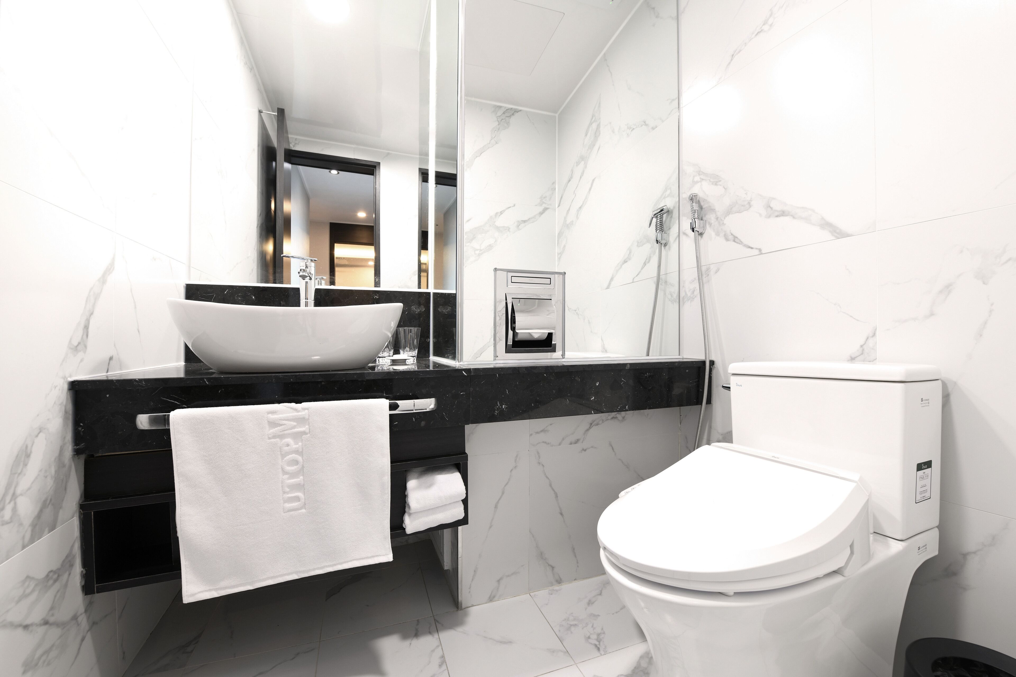 Un baño moderno con un lavabo blanco, encimera negra y un inodoro.