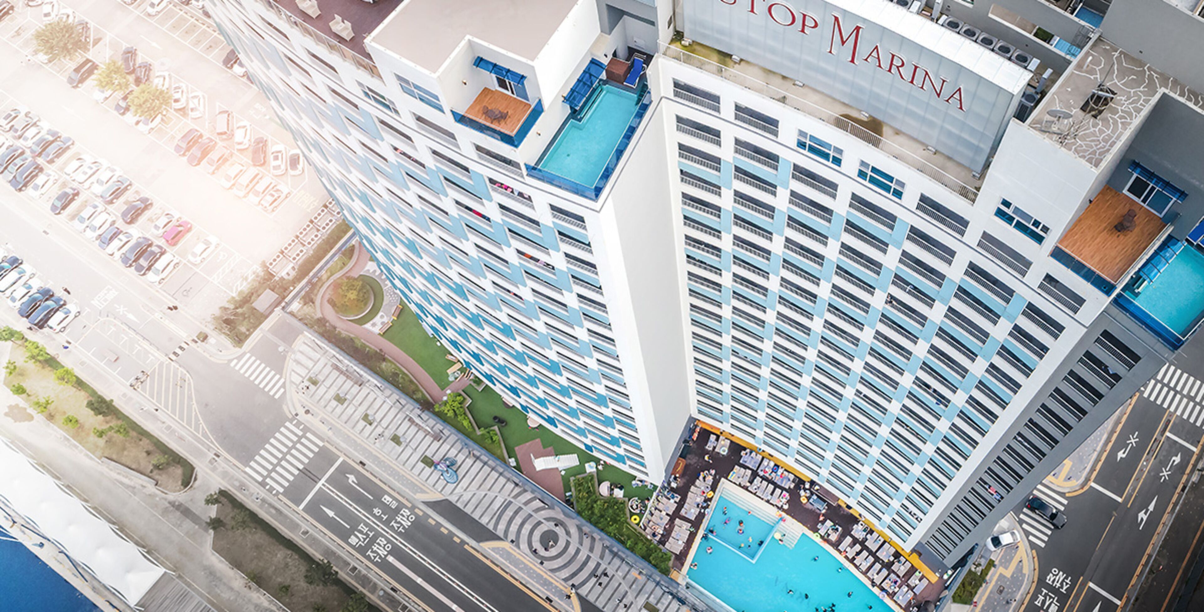 Ett högt hotell med poolområde, flera balkonger och en väl synlig skylt med texten ”Stopp Marina”.