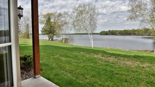 A lakeside view from a porch with a wooden railing, a lamp, and a grassy lawn. - Unit 411a 1 Bd/ 1 Ba Condo 1 Bedroom Condo by RedAwning (Birchwood)