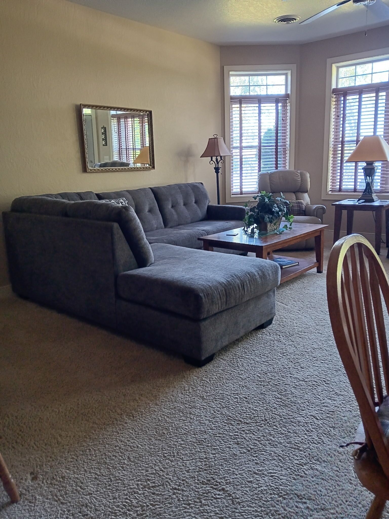 A living room with a sectional sofa, a coffee table, a lamp, and a chair.