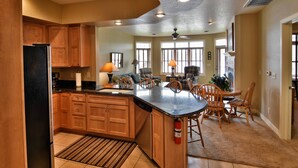 A spacious kitchen with wooden cabinets, a large island, and a dining area with chairs and a table. - Unit 411a 1 Bd/ 1 Ba Condo 1 Bedroom Condo by RedAwning (Birchwood)