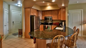 A kitchen with wooden cabinets, a stainless steel refrigerator, a microwave, and a granite countertop. - Unit 411a 1 Bd/ 1 Ba Condo 1 Bedroom Condo by RedAwning (Birchwood)