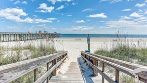 A wooden boardwalk leading to a beach with a clear sky and clouds. - Amelia by the Sea Oceanfront Condo with Access to Private Fishing Pier by RedAwning (Fernandina Beach)