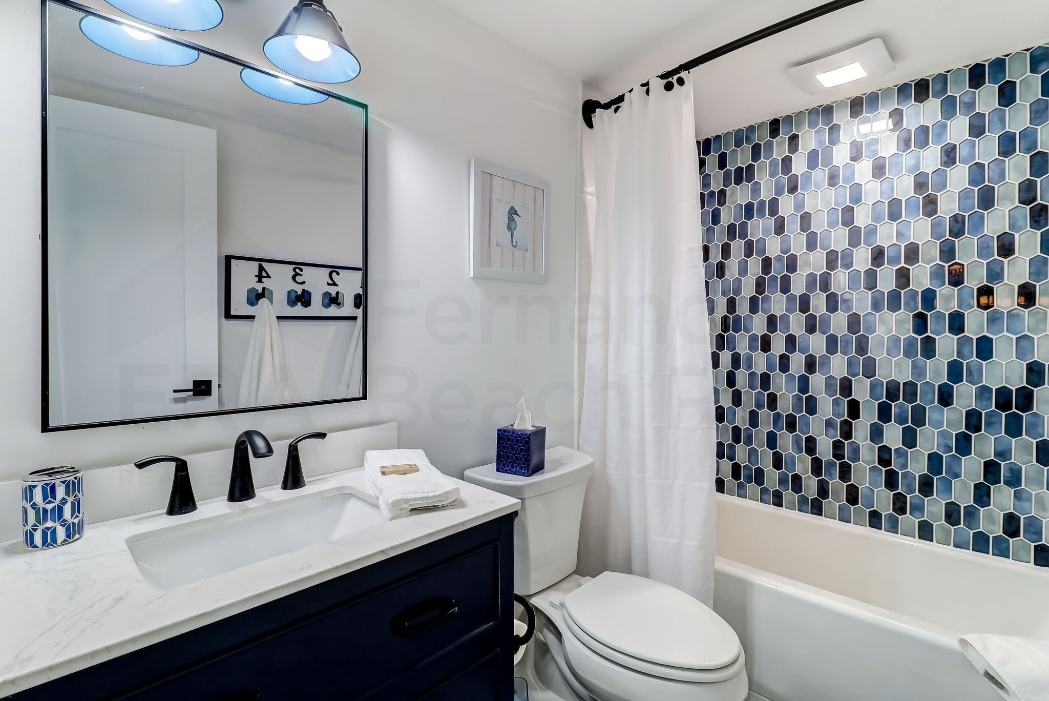 Une salle de bain avec un lavabo blanc, des robinets noirs, des toilettes blanches et une baignoire.