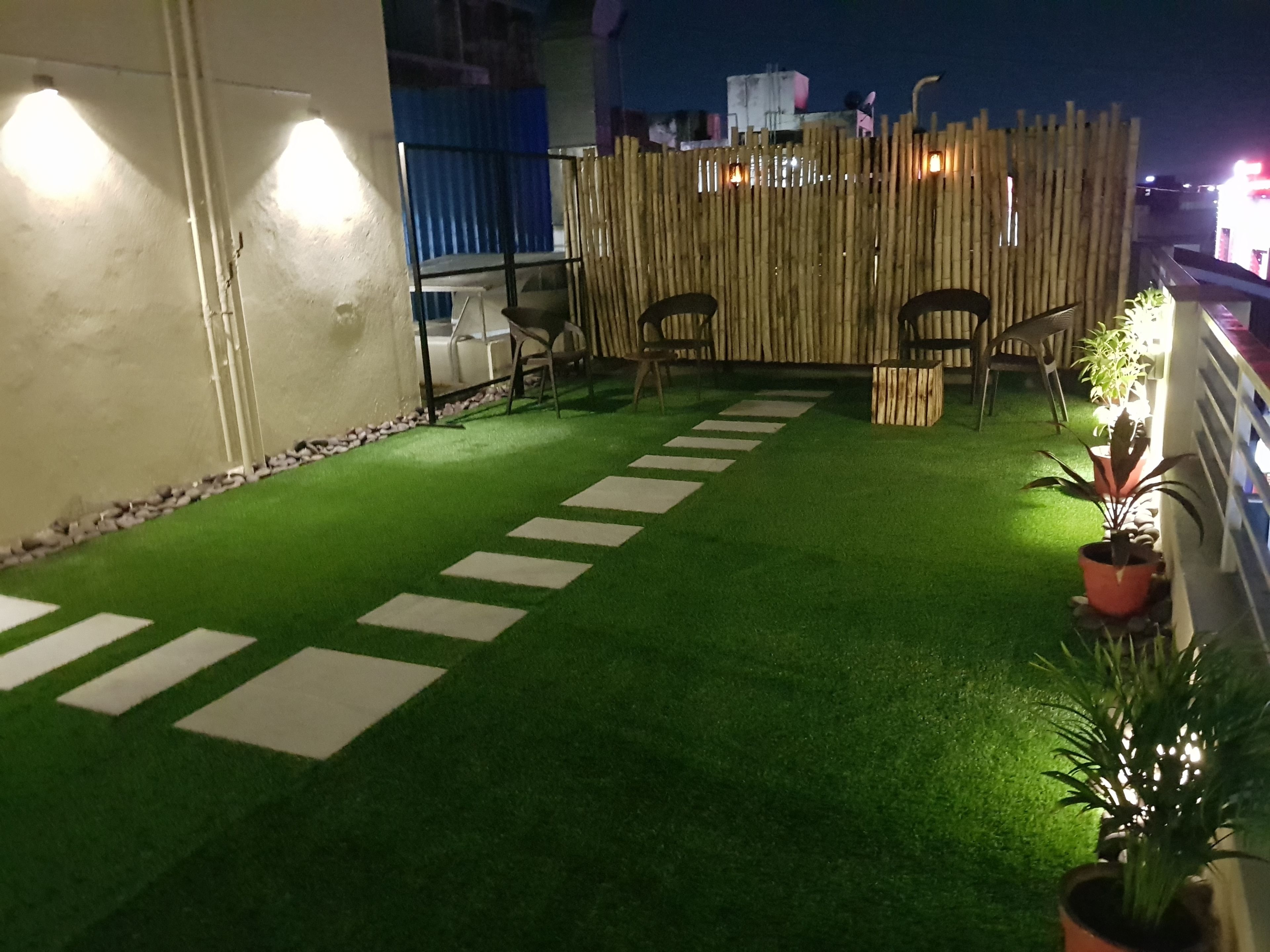 Un jardín en la azotea con césped artificial, piedras para caminar y plantas en macetas.