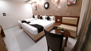 A hotel room with a large bed, a bedside table, a chair, and a small table with a plant. - Liza Regency (Chennai)