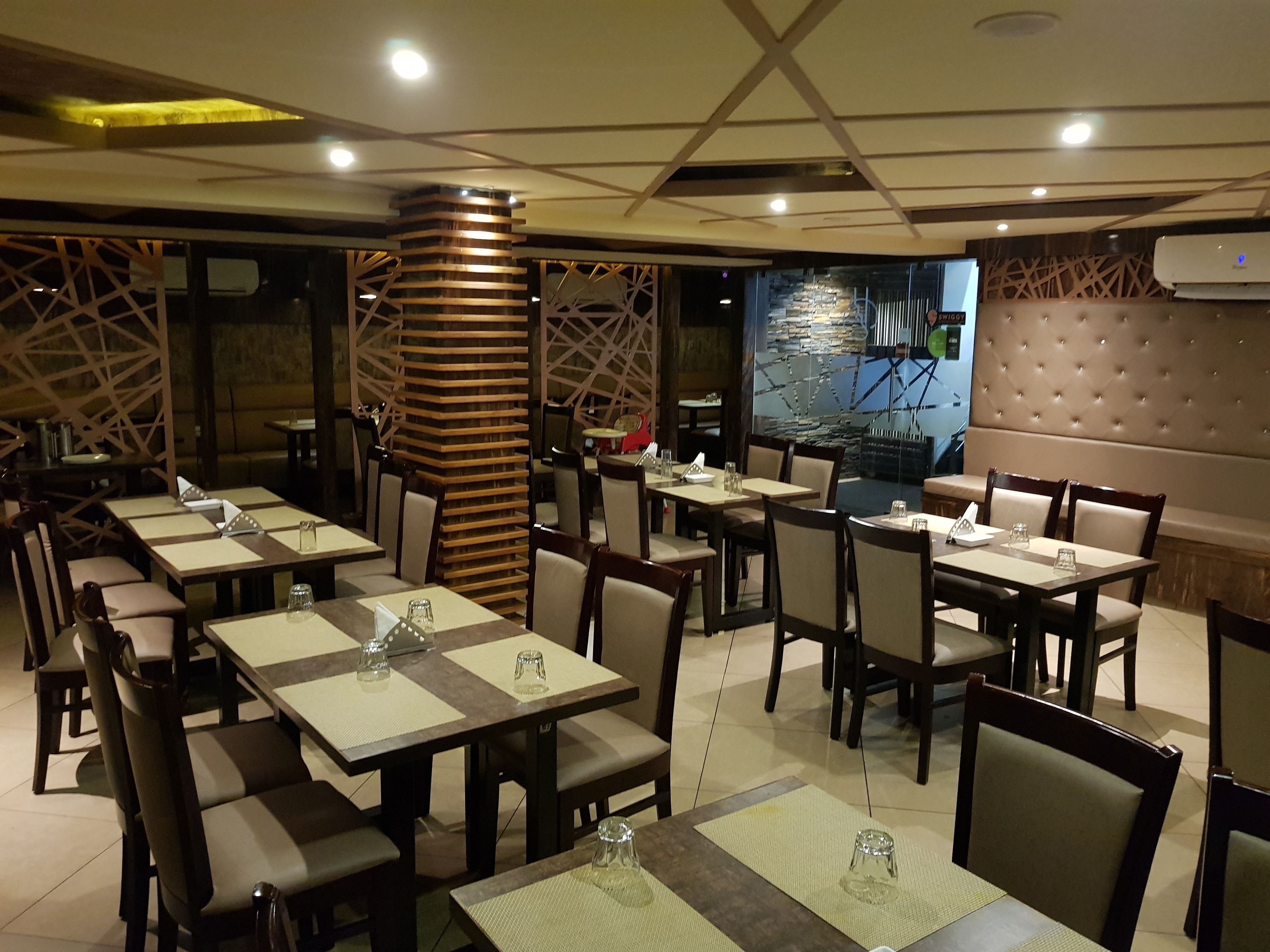Ein Restaurant mit mehreren Tischen und Stühlen, einer dekorativen Säule und einer Steinwand mit Wandmalerei.